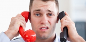 Man holding two phones with a disgusted look on his face