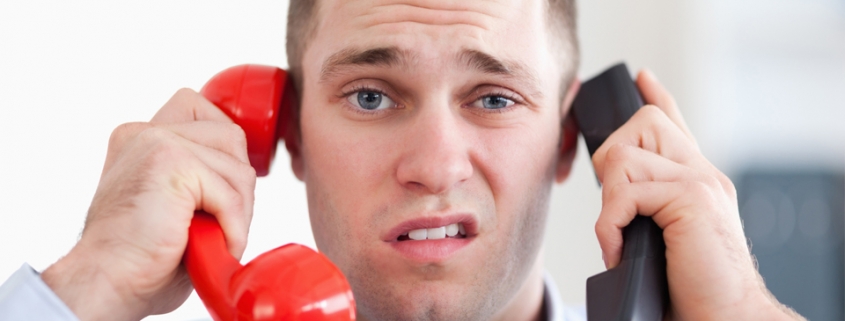 Man holding two phones with a disgusted look on his face