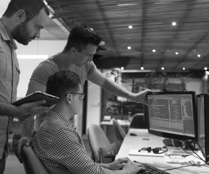 An IT team gathers around a computer
