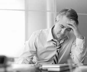 A frustrated businessman with a loose tie going over records